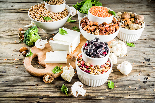 Healthy plant vegan food, veggie protein sources: Tofu, vegan milk, beans, lentils, nuts, soy milk, spinach and seeds. Old wooden background copy space