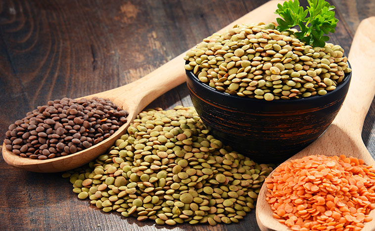Composition with bowl of lentils on wooden table.